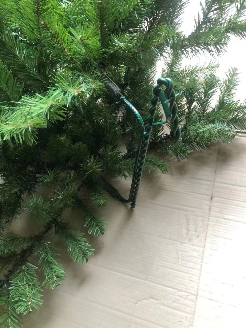 Close-up of artificial Christmas tree branch and steel hook attachment on metal frame with realistic green PVC needles