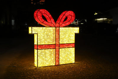 Large warm white LED gift box display with glowing red bow and ribbon, designed for commercial holiday décor and outdoor light installations